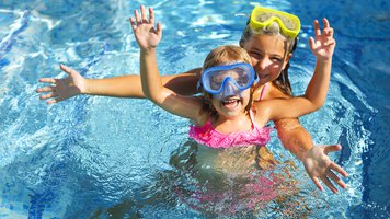 Two funny girls playing in swimming pool